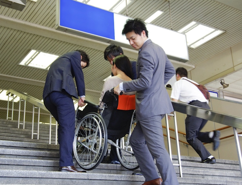 バリアフリー対策をしていない階段や段差のあるところで車椅子を補助している人たちの様子