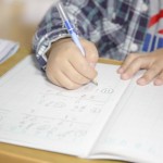 子供が鉛筆で学習ノートに文字を書く練習をしている、書き取りの練習をしているイメージ画像。