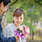 恋愛関係にある男性から花束を受け取りプロポーズをされて喜んでいる女性のイメージ。