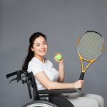 車いすテニスにチャレンジしようとしている笑顔の女性の明るくてさわやかで活動的な画像。情報にもバリアフリーを。障がい者とその関係者のコミュニティ、情報サイト。ナレバリ