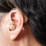 コンパクトな補聴器を耳につけている男性のイメージ写真。情報にもバリアフリーを。障がい者とその関係者のコミュニティ、情報サイト。ナレバリ