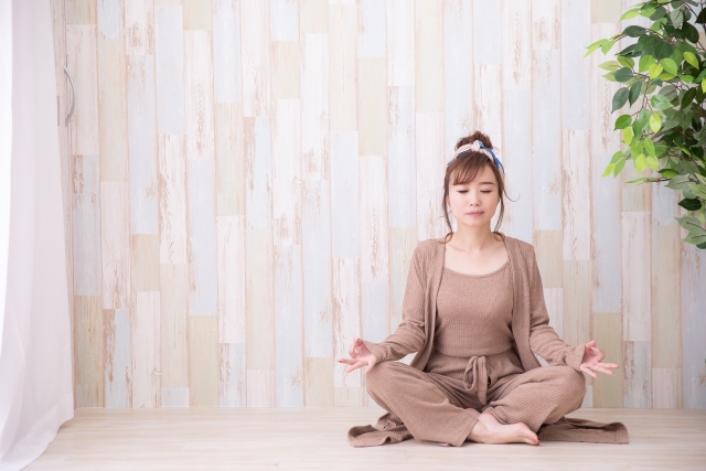 瞑想のヨガのポーズをとり、気持ちをリフレッシュ、リラックスさせている落ち着いた時間を過ごす女性のイメージ画像。