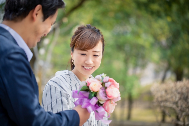 恋愛関係にある男性から花束を受け取りプロポーズをされて喜んでいる女性のイメージ。
