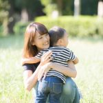 2歳の子供と公園で遊んでいる中で愛情をもって優しく抱きかかえるお母さんのイメージ。情報にもバリアフリーを。障がい者とその関係者のコミュニティ、情報サイト。ナレバリ