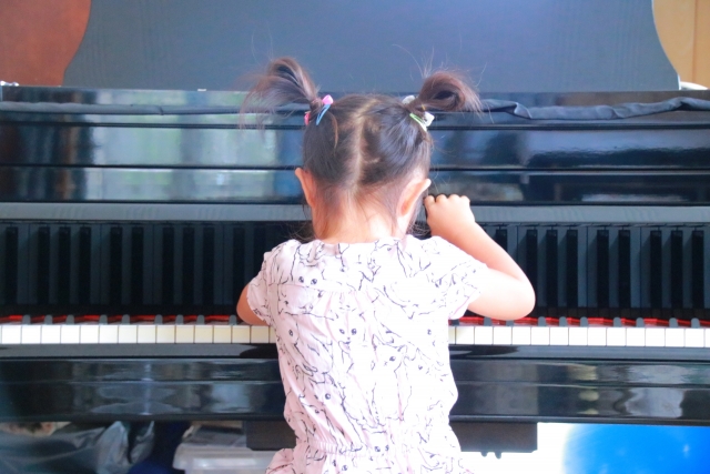 慣れない手つきながらピアノを一生懸命に練習している小さな女の子のイメージ画像。情報にもバリアフリーを。障がい者とその関係者のコミュニティ、情報サイト。ナレバリ