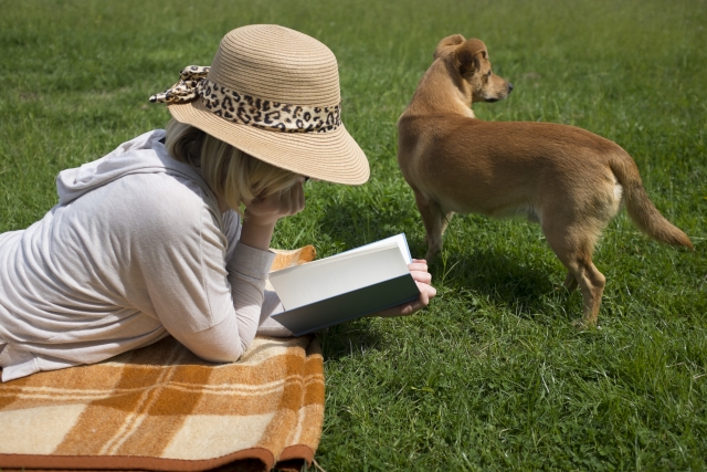 原っぱでリラックスしながら愛犬と読書を楽しみ女性の画像。情報にもバリアフリーを。障がい者とその関係者のコミュニティ、情報サイト。ナレバリ